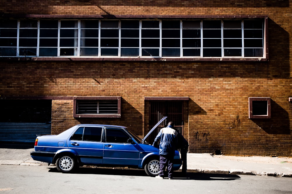 two men fixing up blue car