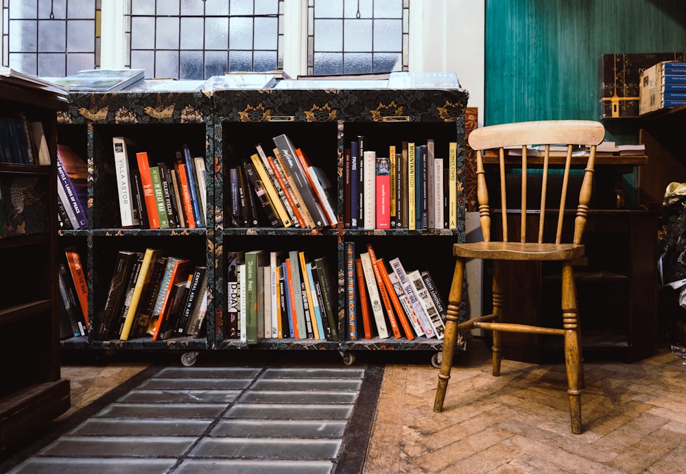 brown wooden windsor chair near black wooden bookshelf