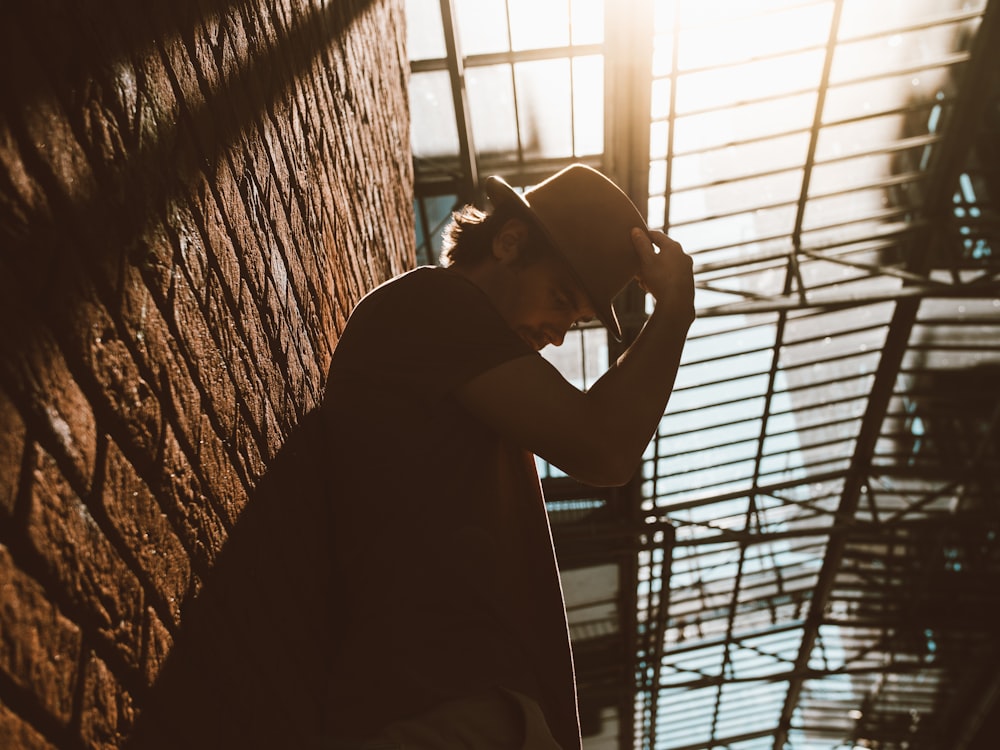 man leaning on brown wall