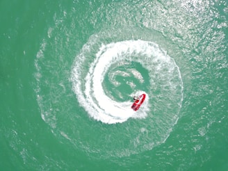 aerial photography of red personal watercraft circling on water at daytime