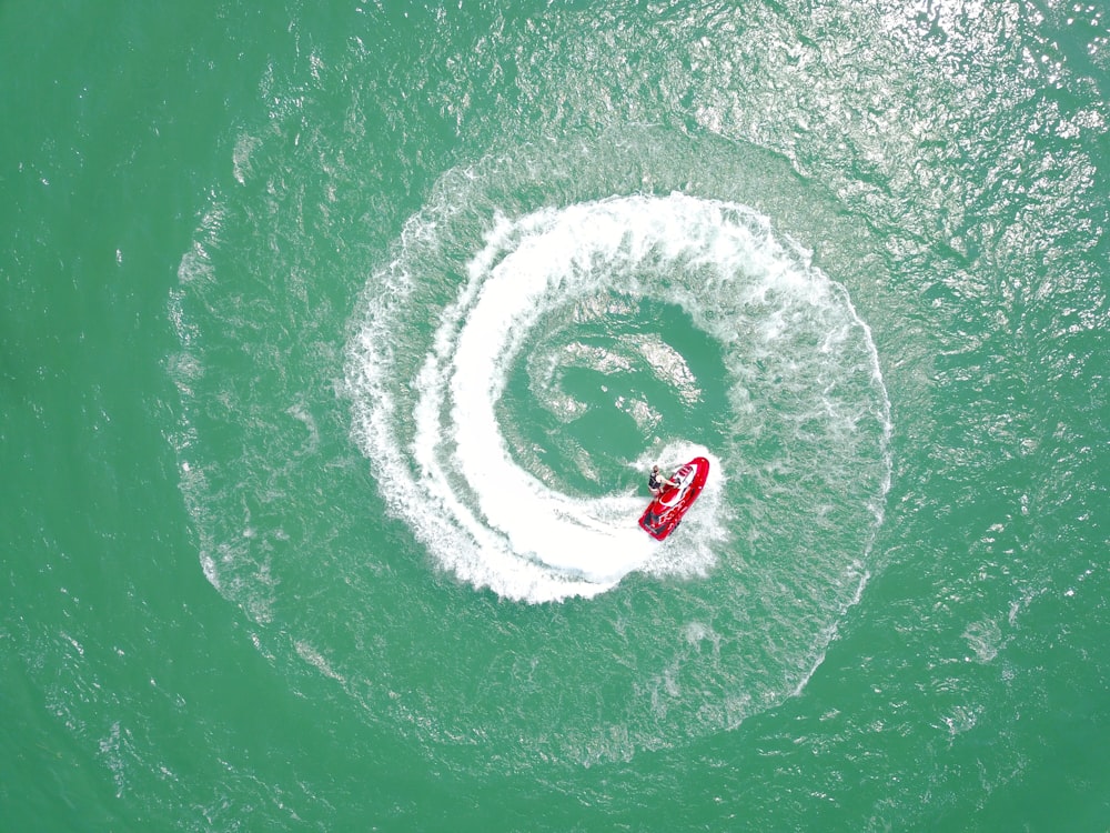fotografia aerea di moto d'acqua rossa che volteggia sull'acqua durante il giorno