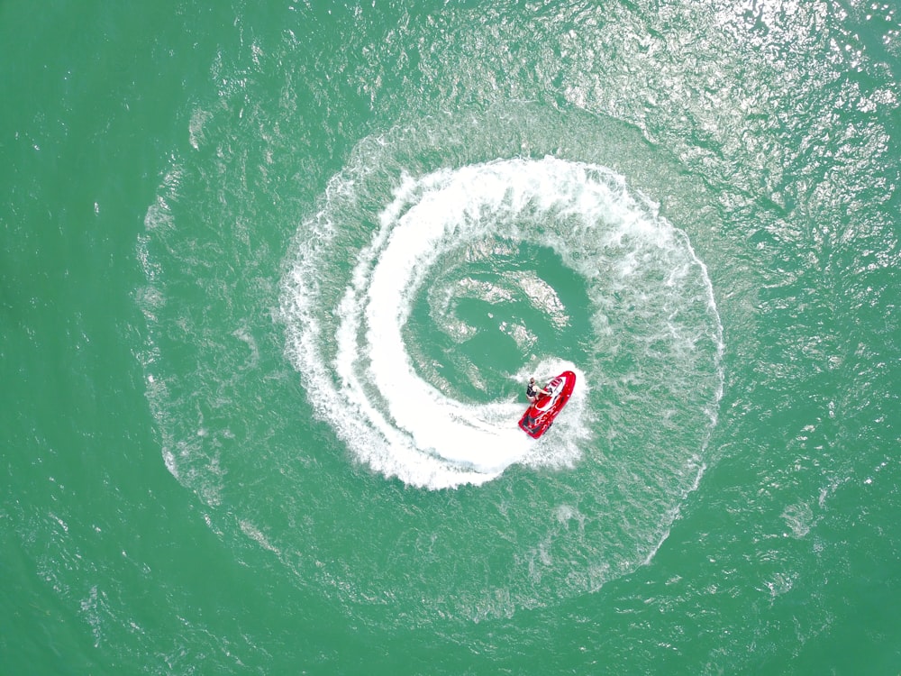 aerial photography of red personal watercraft circling on water at daytime