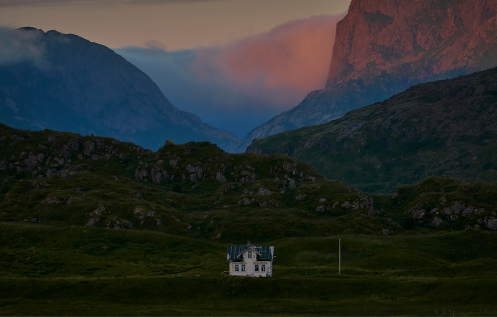 white concrete house near mountain under gray sky