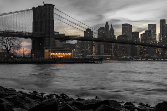 calm body of water beside concrete bridge in Brooklyn Bridge Park United States