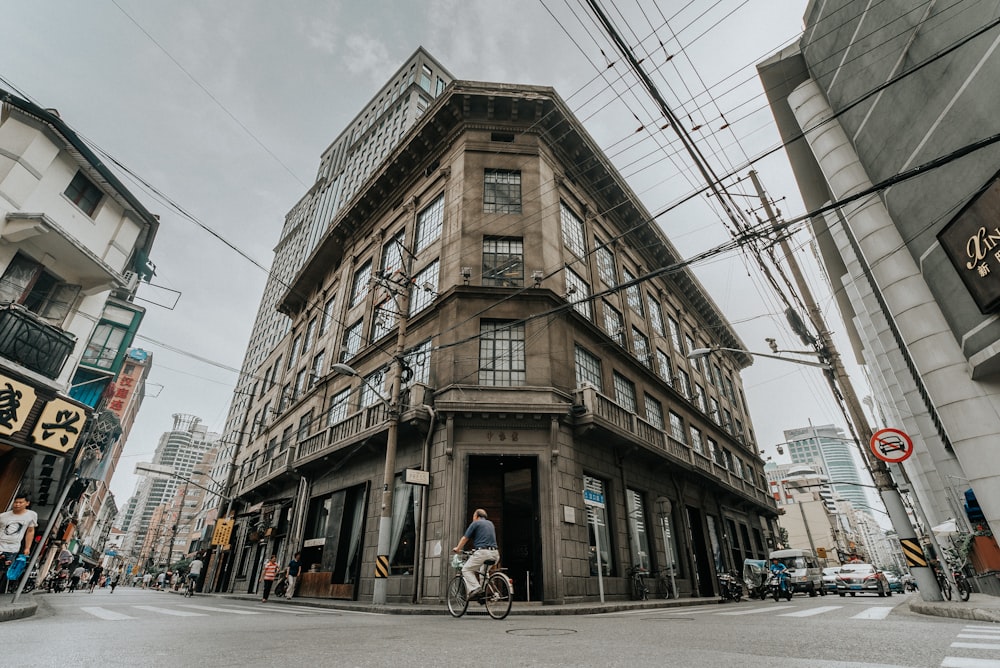 a man riding a bike down a street next to a tall building