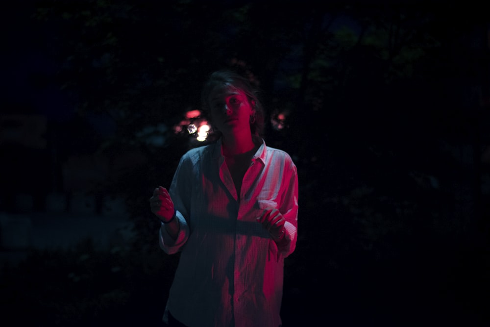 a woman standing in the dark holding a lit object