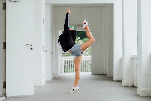 Taekwondo student practicing a high kick in a bright training hall