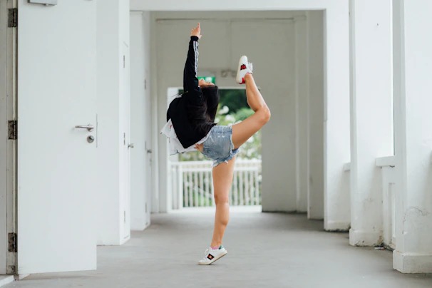 A young student performing a high kick against a plain green background.