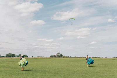 Aerial view of a skydiving dropzone with colorful canopies floating above green fields.
