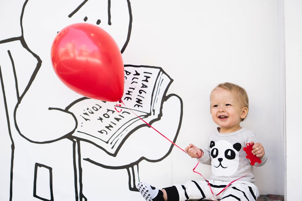 smiling toddler holding red balloon