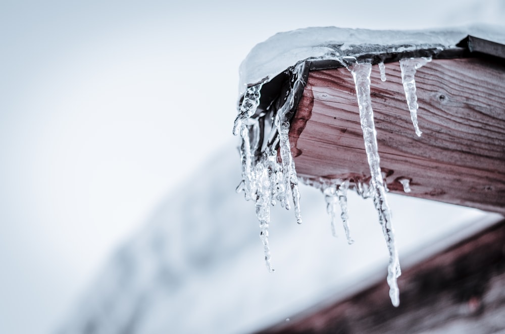 icicles hanging from a wooden post on a snowy day