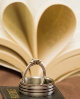 A stack of mixed metal rings on a hand against a backdrop of vintage books.