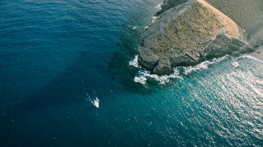 aerial photo of boat sailing on sea near rock mountain in Cabo de Gata-Níjar Natural Park Spain
