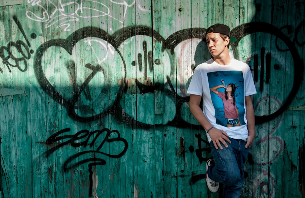 man leaning on graffiti painted wall