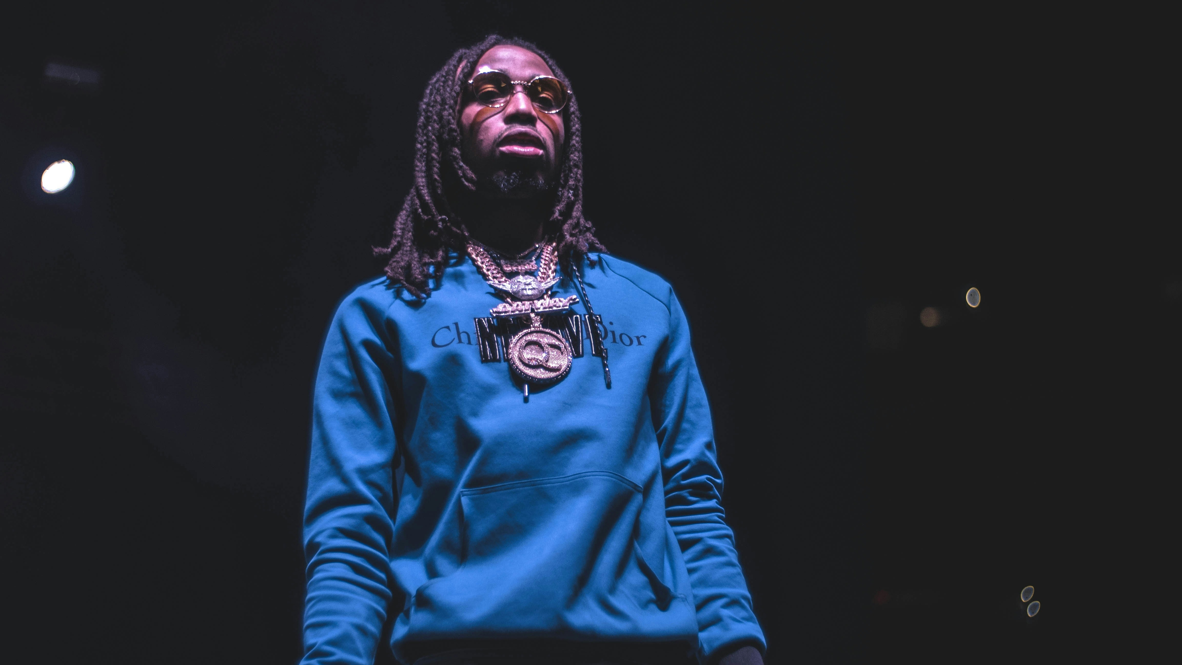 Male rap artist in dark hoodie in dimly lit urban environment, moody atmospheric low-key lighting