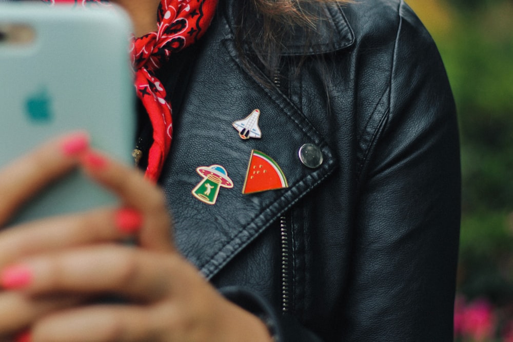 person wearing black leather jacket holding mobile phone