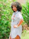 Plus size woman smiling confidently wearing a handmade crochet outfit outdoors.