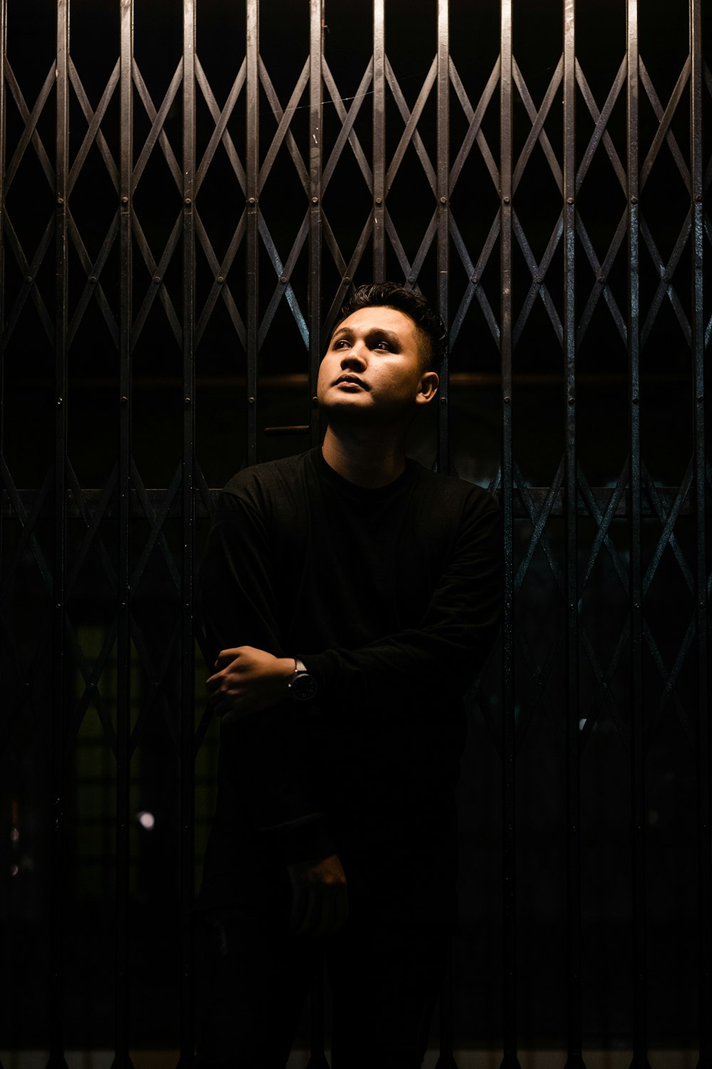 minimalist photography of man standing in front metal gate