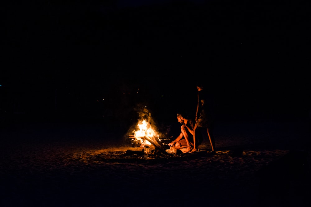 three person sitting near bornfire