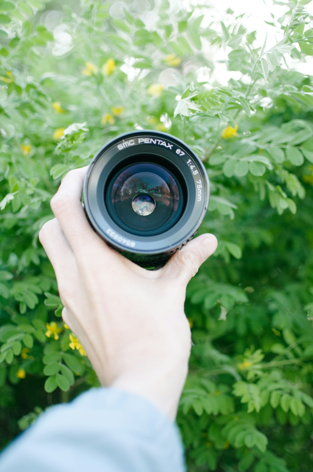 person holding black Pentax zoom lens