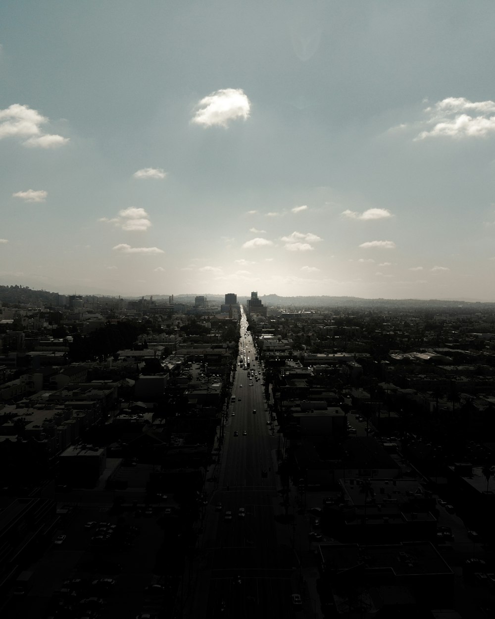 Fotografía en escala de grises de la ciudad con edificios de gran altura que ven la carretera