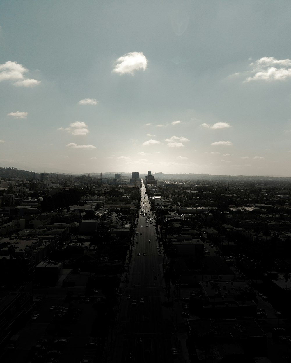 Photographie en niveaux de gris de la ville avec des immeubles de grande hauteur regardant la route