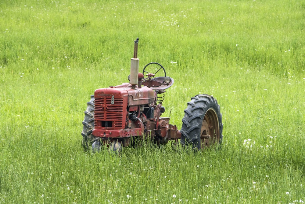 Trattore rosso lasciato nel campo d'erba