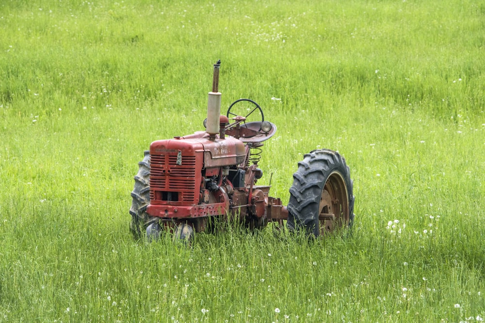 tracteur rouge laissé dans un champ d’herbe
