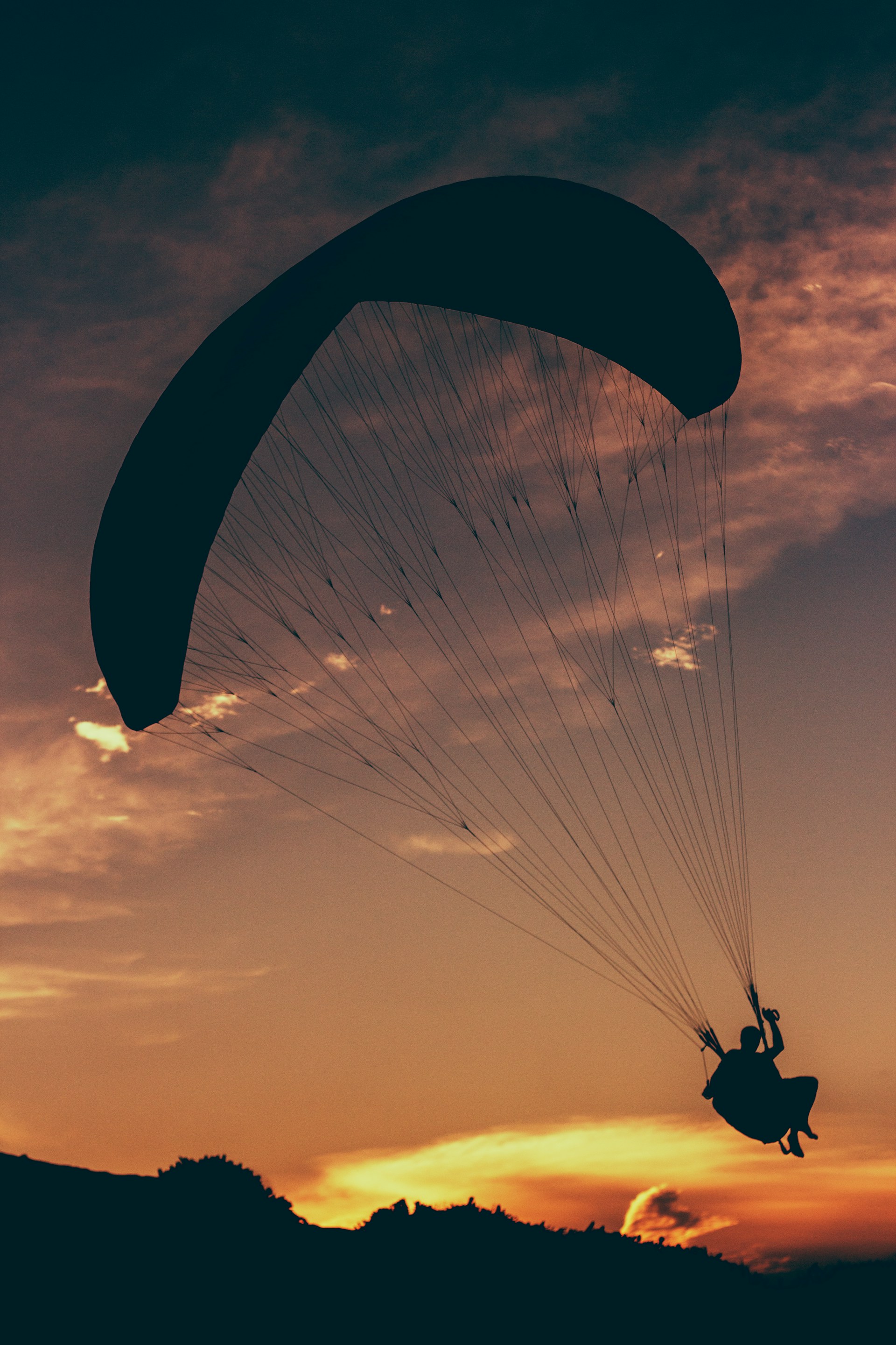silhouette of man in parachute at golden hour