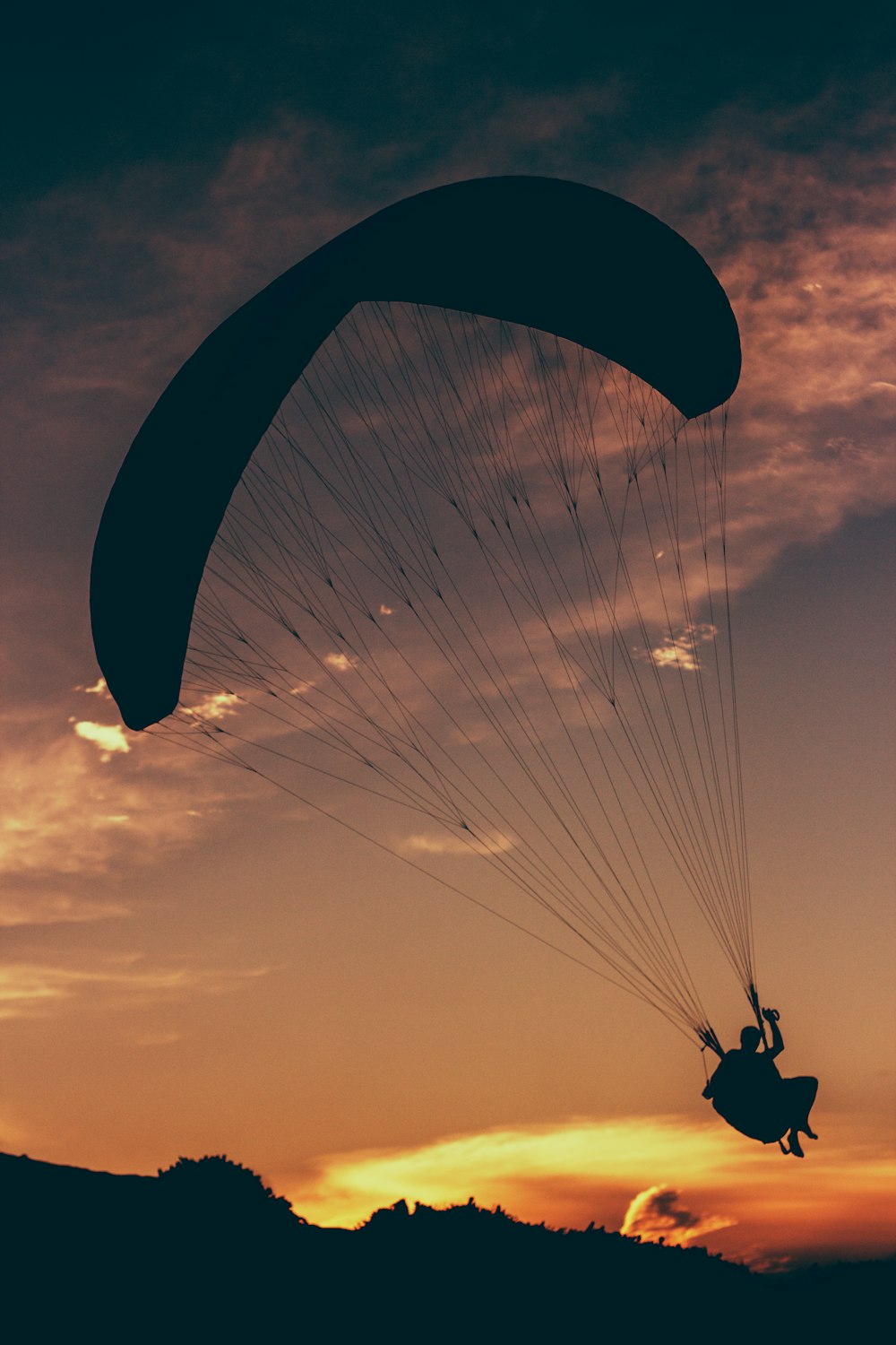 silhouette of man in parachute at golden hour