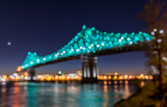 suspension bridge with teal lights during nighttime in Jacques-Cartier Bridge Canada