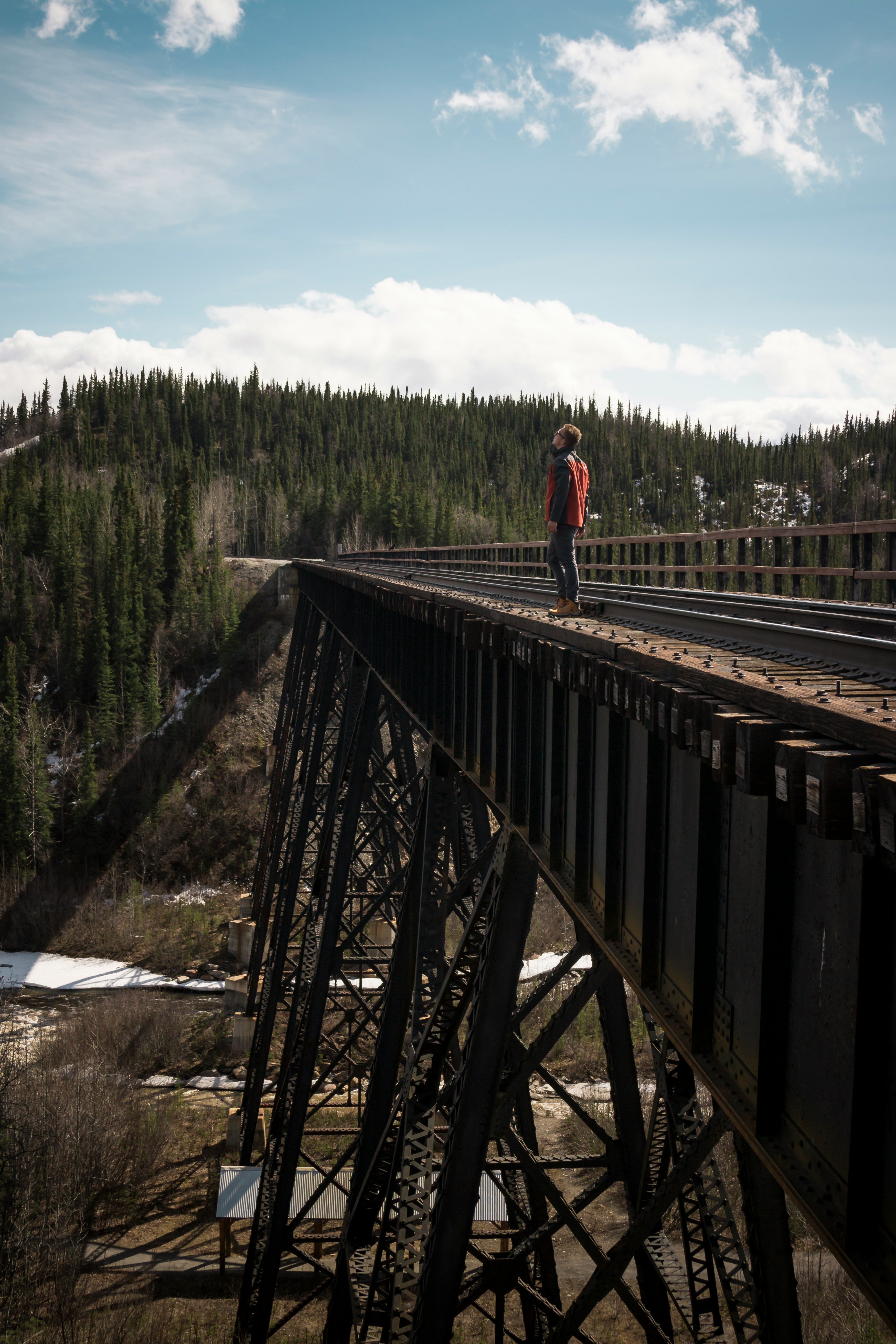 man looking up standing on bridge during daytime
