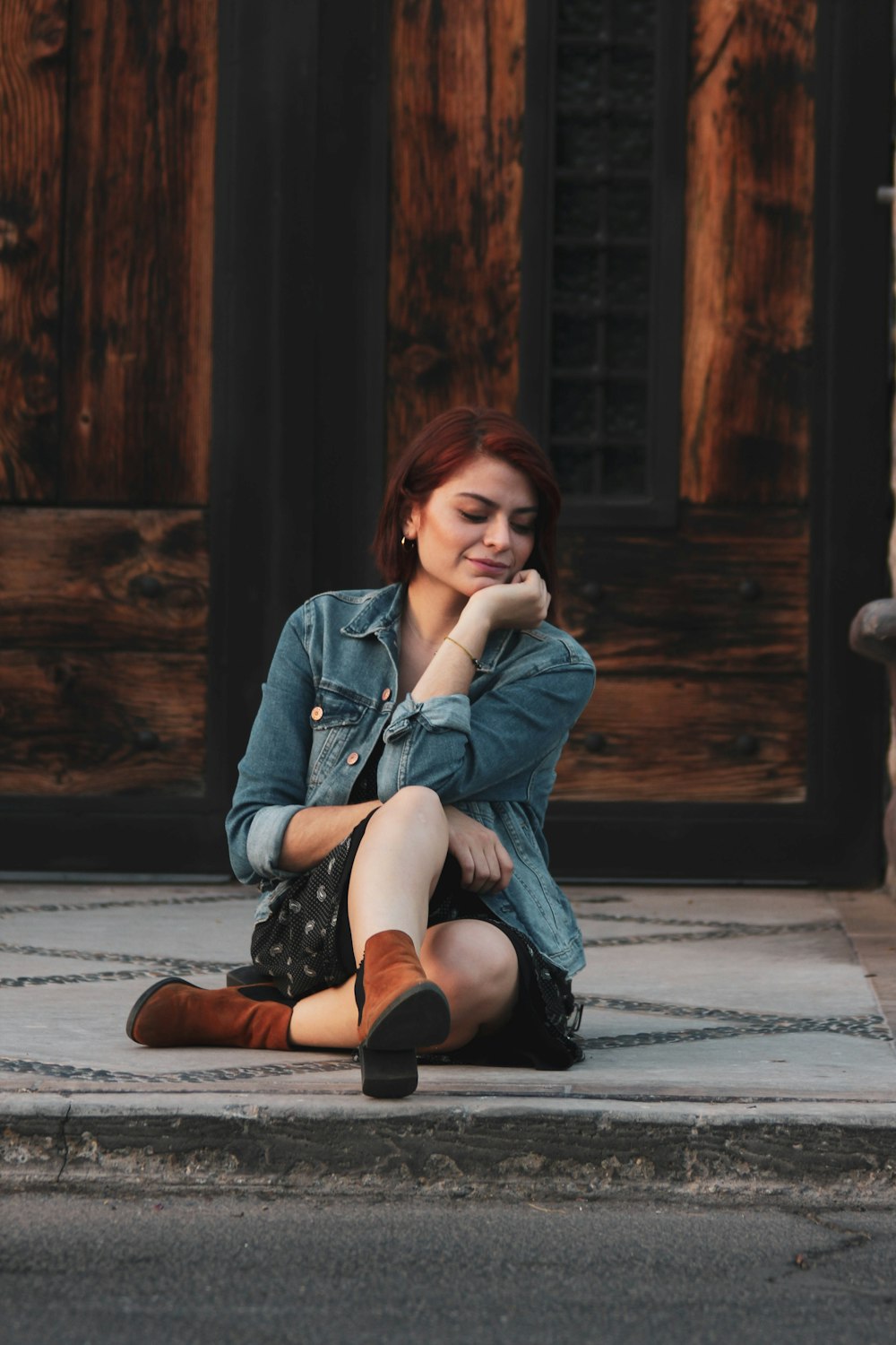 woman wearing blue denim jacet sitting on pavement