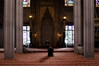 three men sitting inside mosque