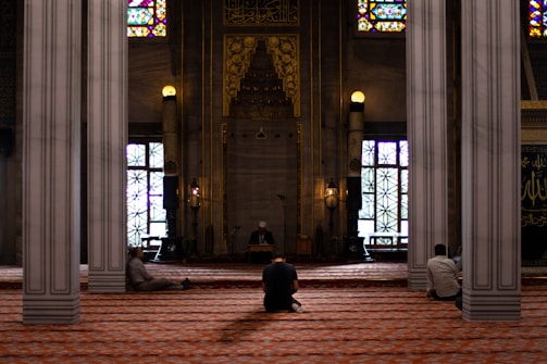 three men sitting inside mosque