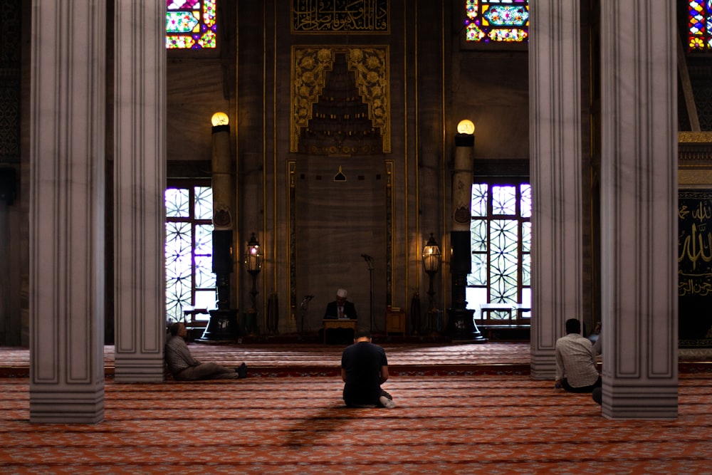 tre uomini seduti all'interno della moschea