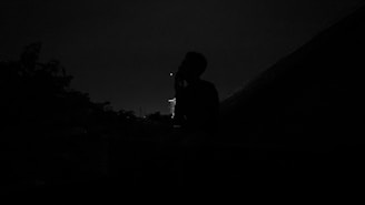 A calm outdoor setting at dusk with a silhouette practicing projection astral under a starry sky.