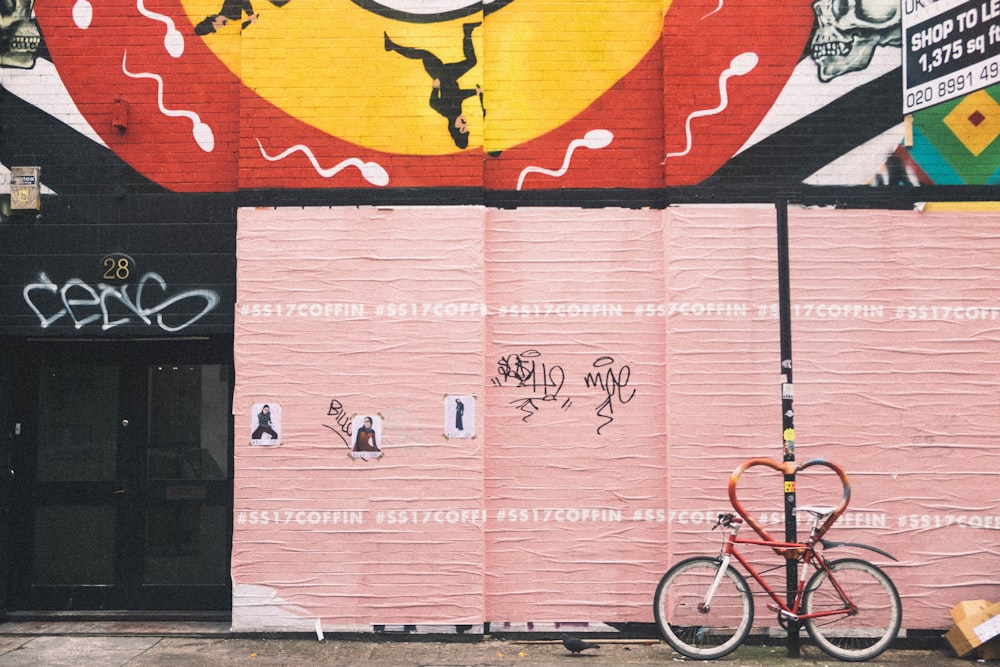 red bicycle near pink wall