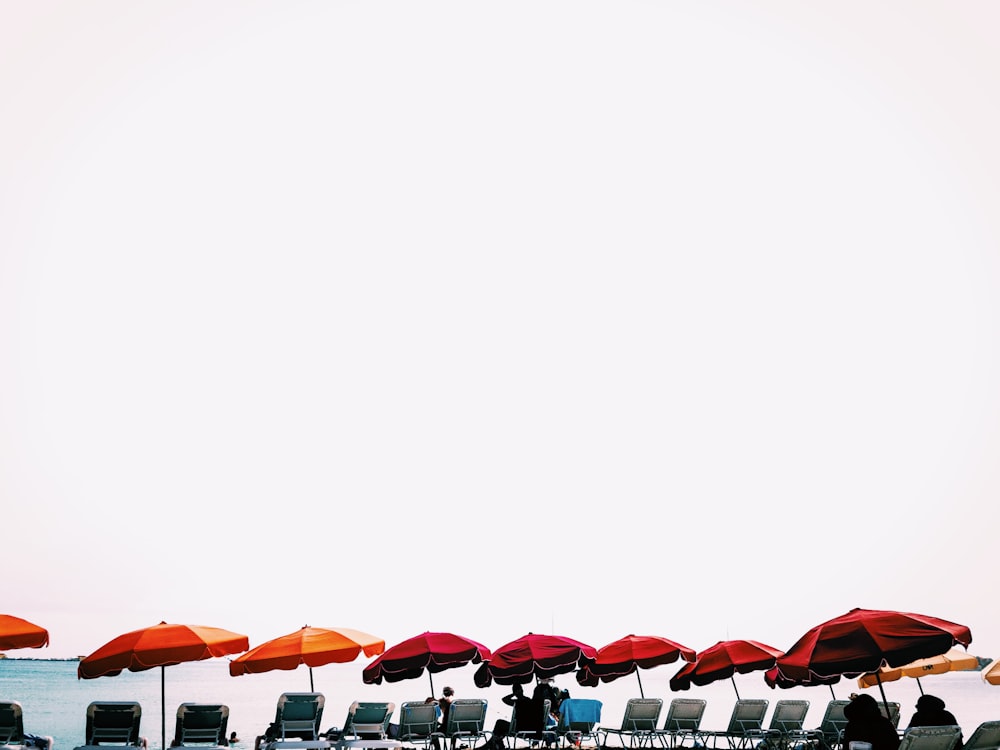 red and orange patio umbrellas in front body of water