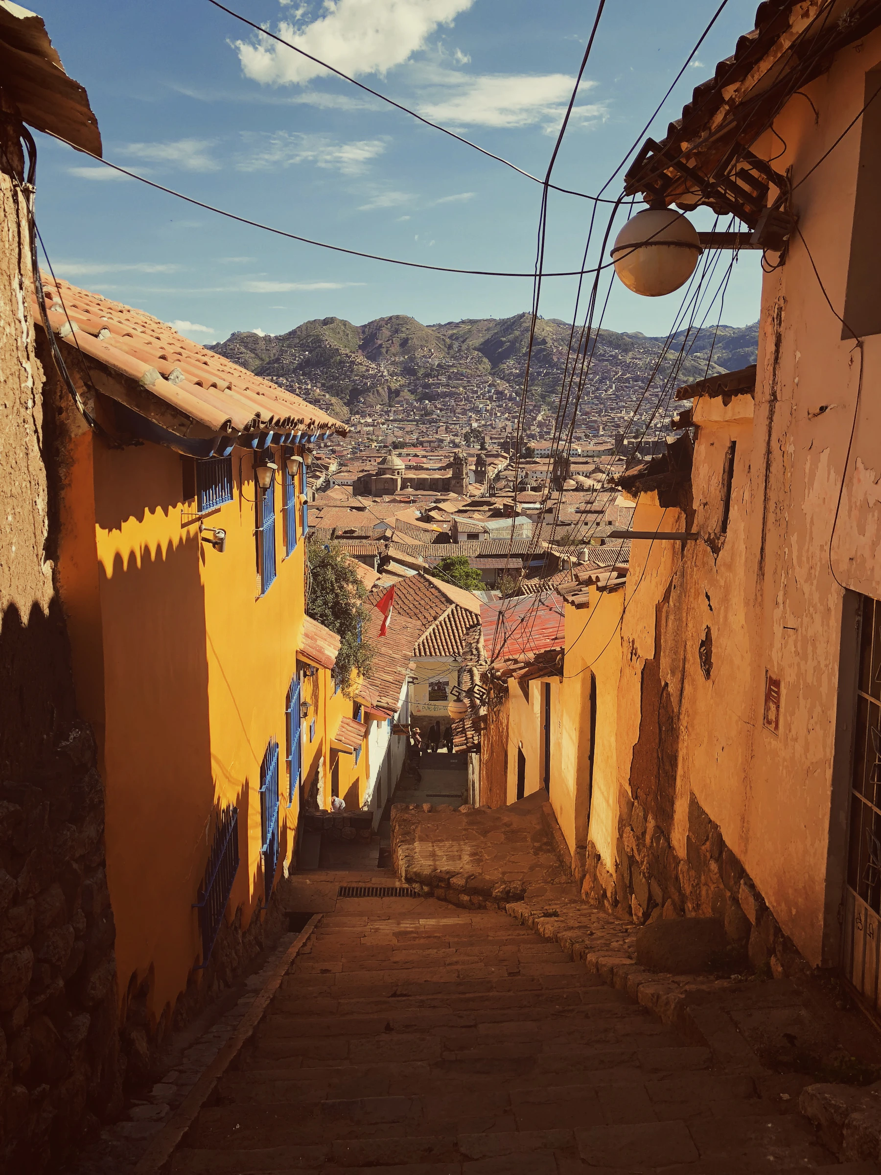 Cusco's terracotta roofs climbing towards green Andean mountains