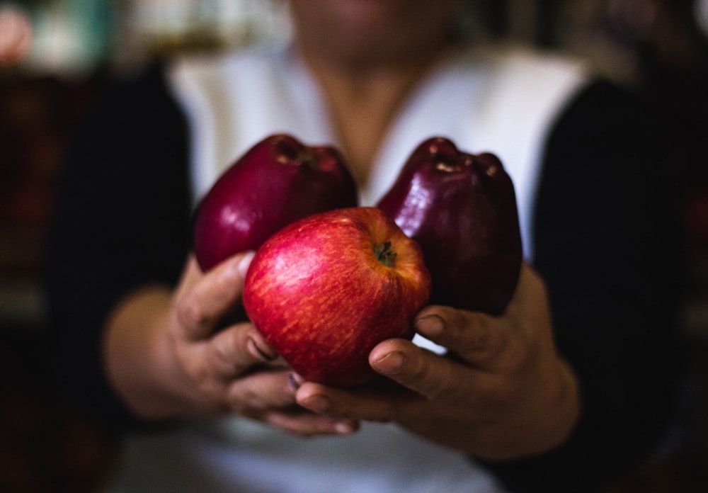 Persona sosteniendo tres manzanas