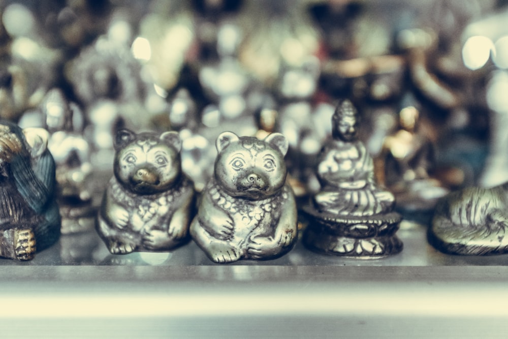 close-up photography of silver-colored bear and Buddha figurines