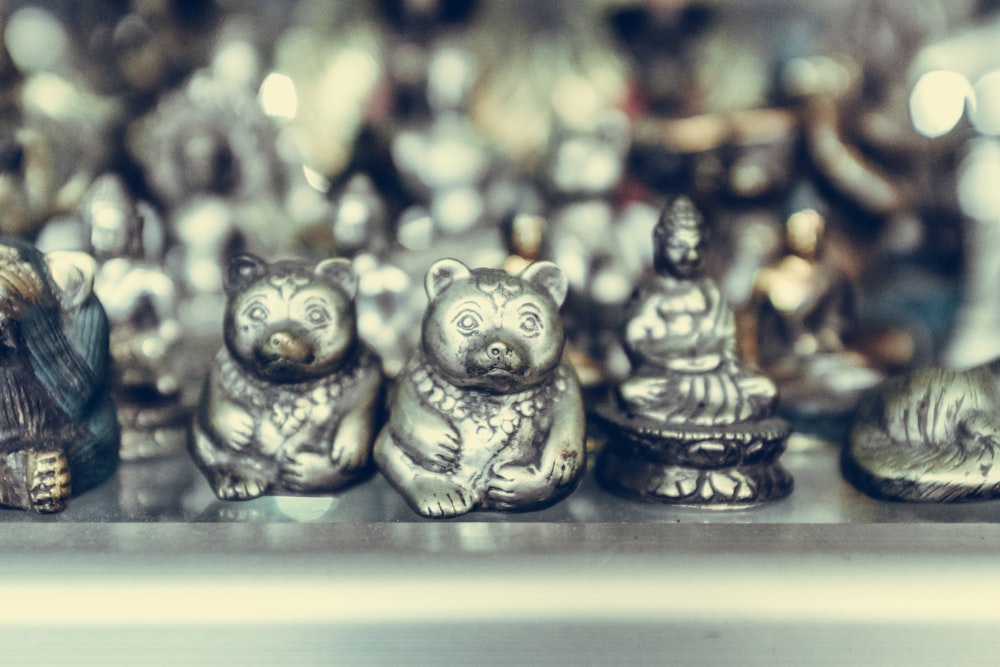 photographie en gros plan de figurines d’ours et de Bouddha de couleur argentée