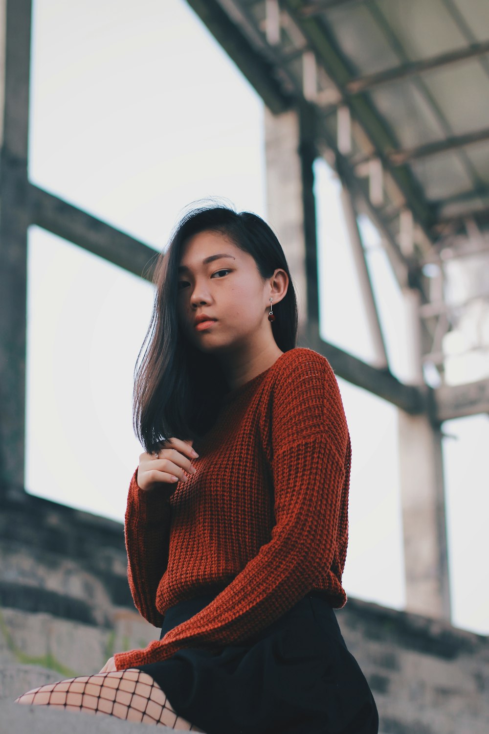 a woman in a red sweater is sitting on a ledge