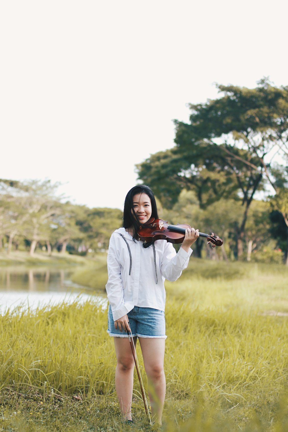 woman standing holding violin near river