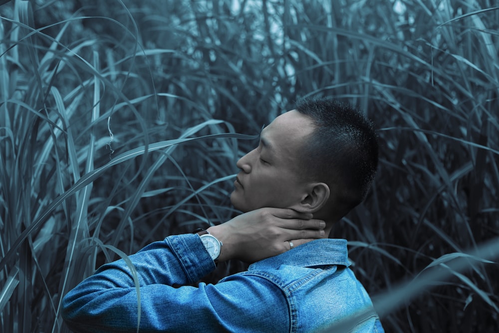 man standing in middle of grass while holding his neck