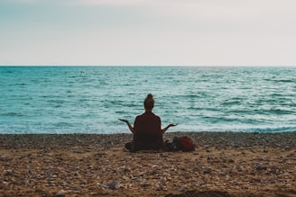 person doing yoga on seashore during daytime