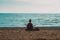 person doing yoga on seashore during daytime