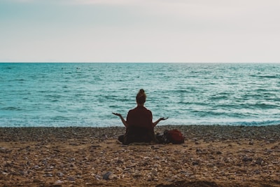 person doing yoga on seashore during daytime