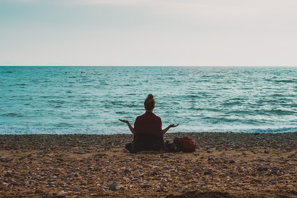 Persona haciendo yoga a la orilla del mar durante el día